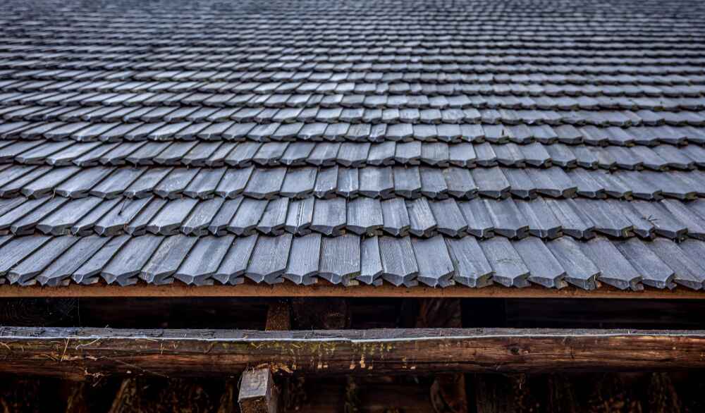 Homeowner demonstrating how do you clean a shingle roof safely using eco-friendly tools